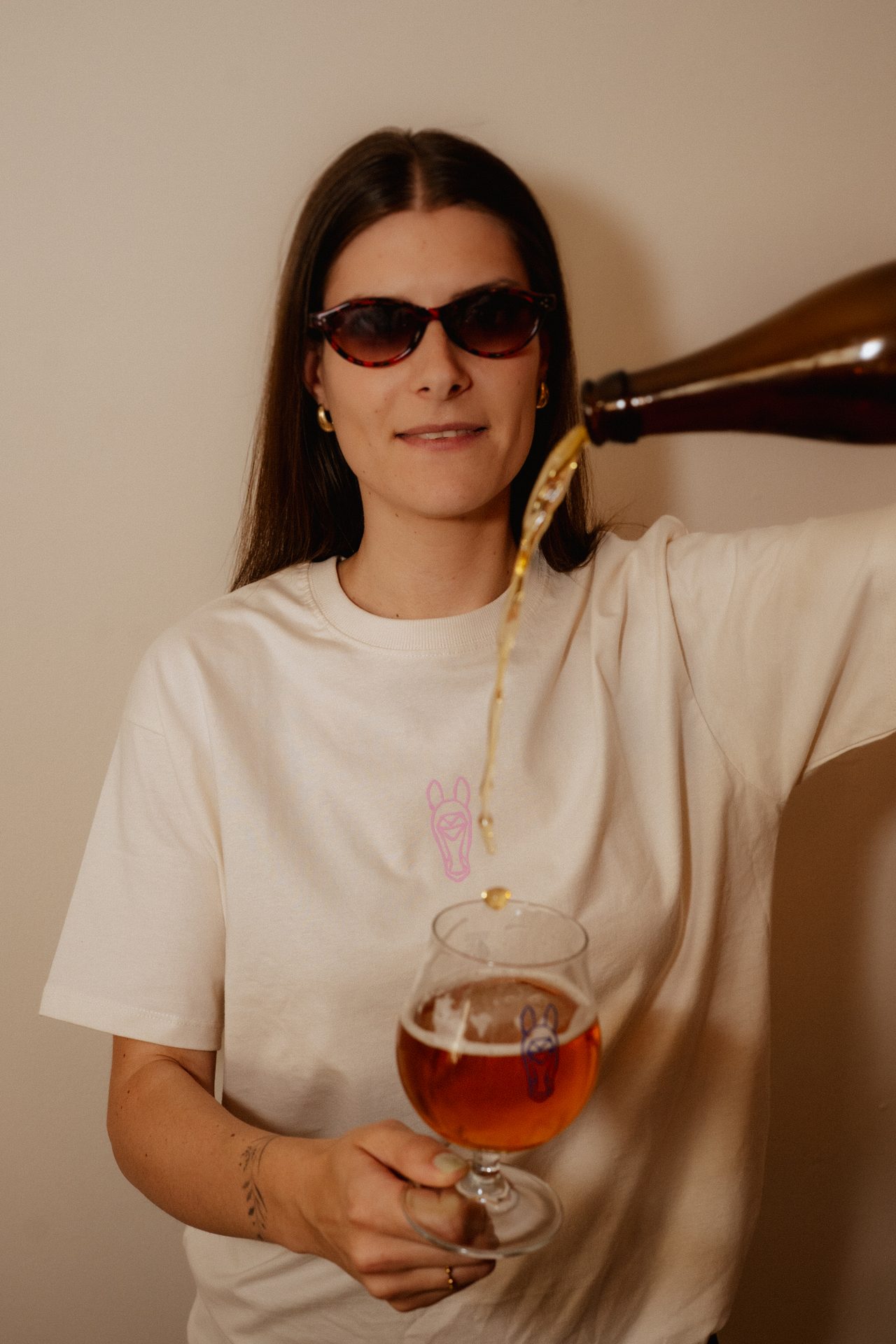 Laura schenkt Bier in ein Tulpenglas mit Brauereigaul-Logo, im Brauereigaul-T-Shirt